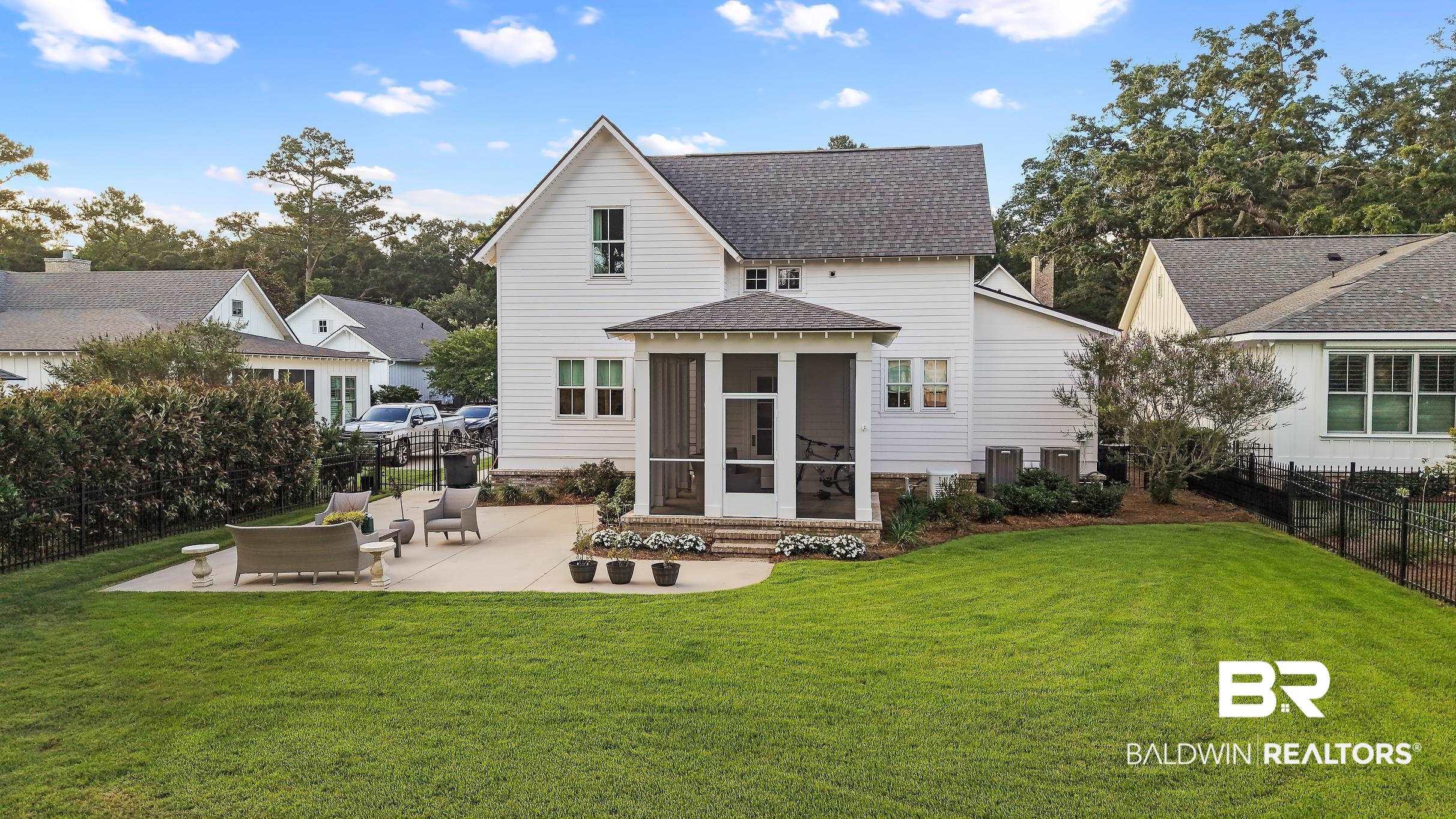 Image 3: Expansive lawn with a concrete patio, a screened porch, and a black metal fence