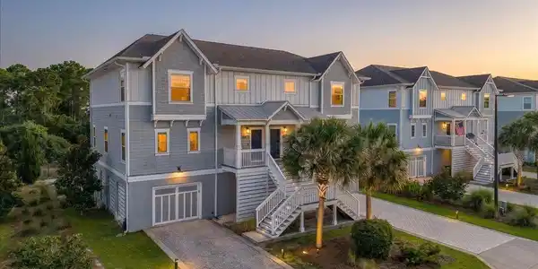 Image 2: Multi-story residential property featuring a gray and white exterior with gabled roofs