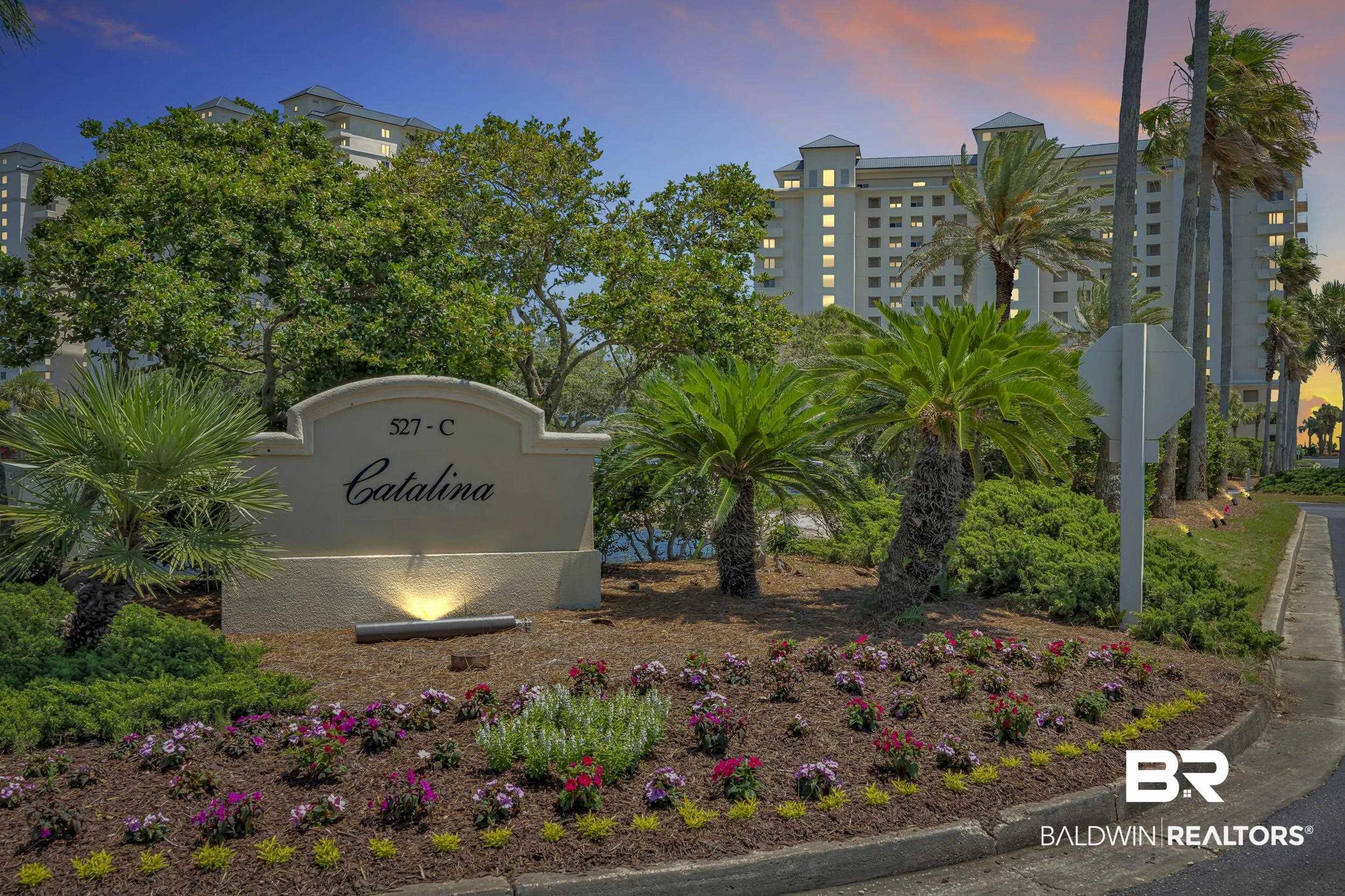 Image 1: Entry monument featuring a stucco finish with integrated lighting, surrounded by a landscaped garden bed with flowering plants and mulch