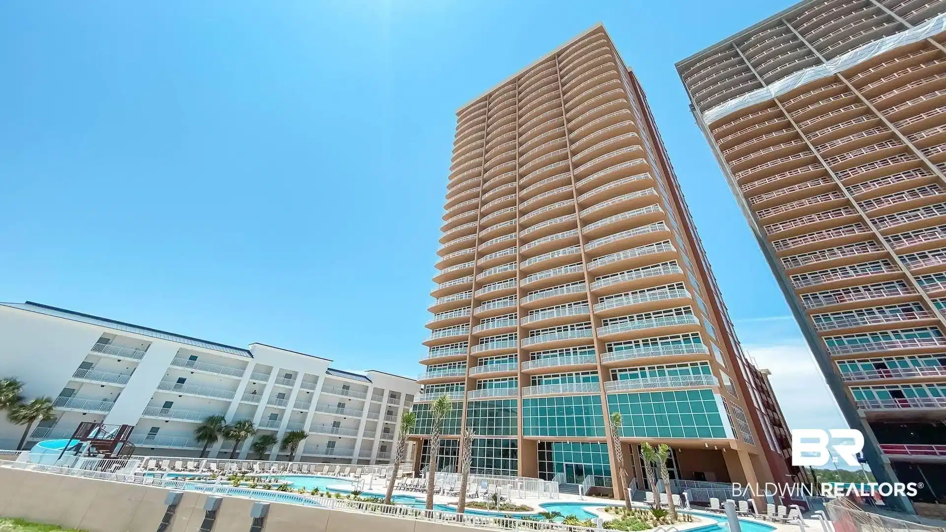 Image 1: Multi-story residential tower featuring numerous private balconies and a ground-level pool complex