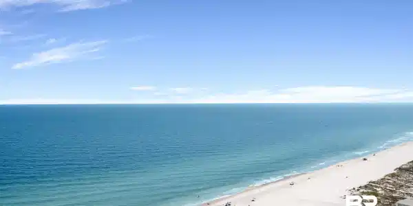 Image 4: Expansive coastal scenery featuring a wide sandy beach, turquoise ocean waters, and a clear horizon