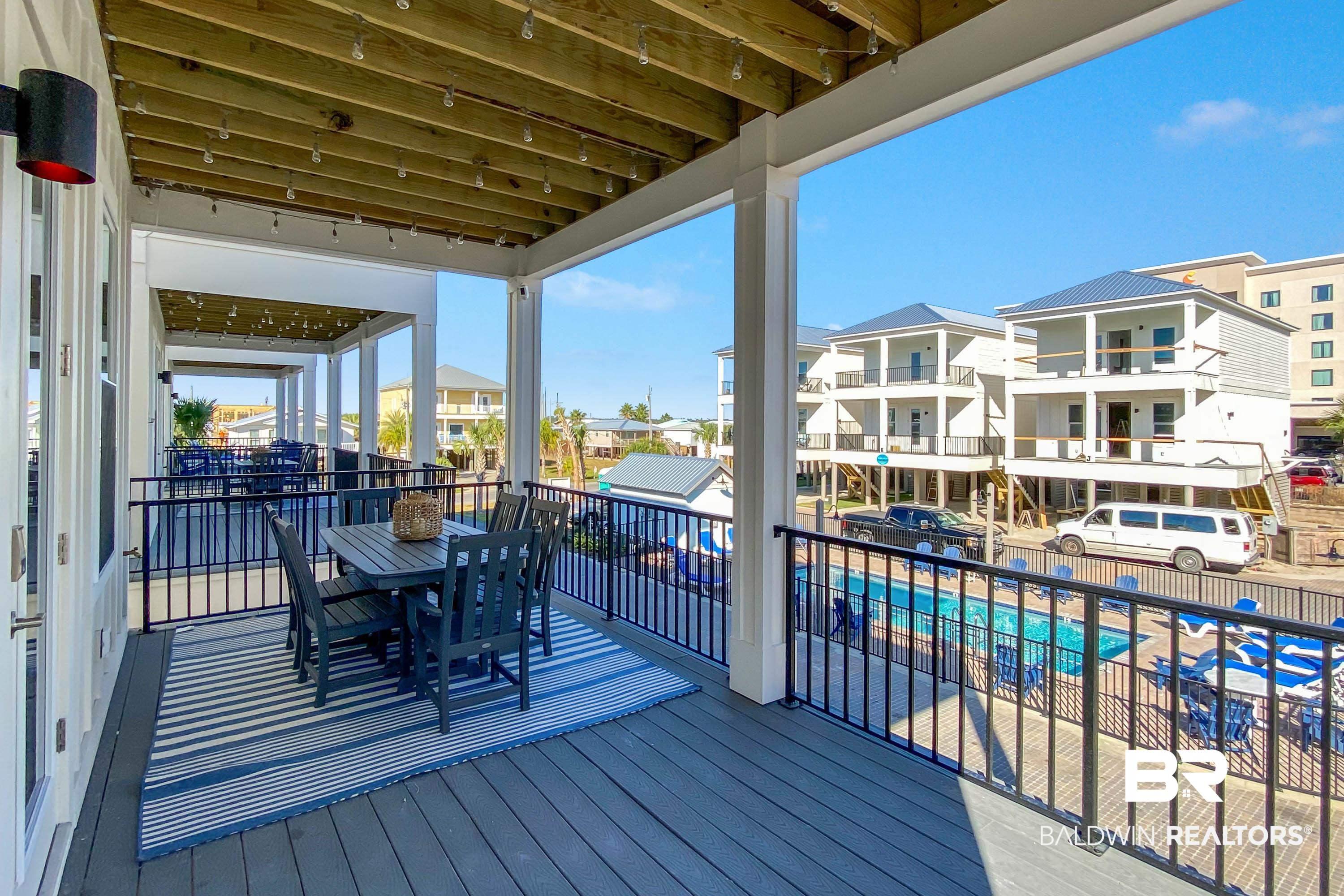 Image 3: Wooden deck with outdoor dining area and a community pool