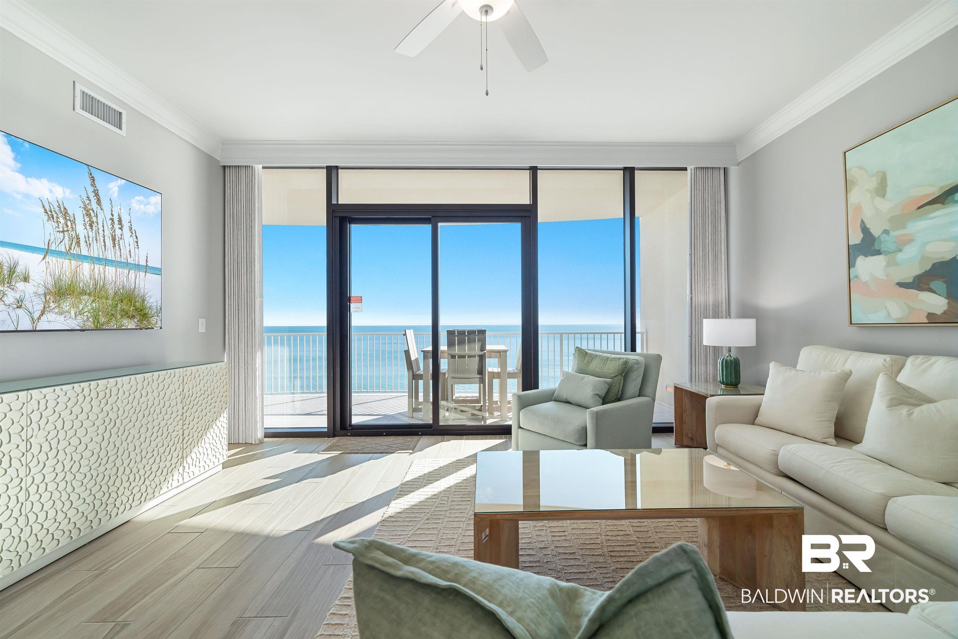 Image 4: Living area featuring a water view, wood finished floors, a wainscoted wall, crown molding, and a wall of windows