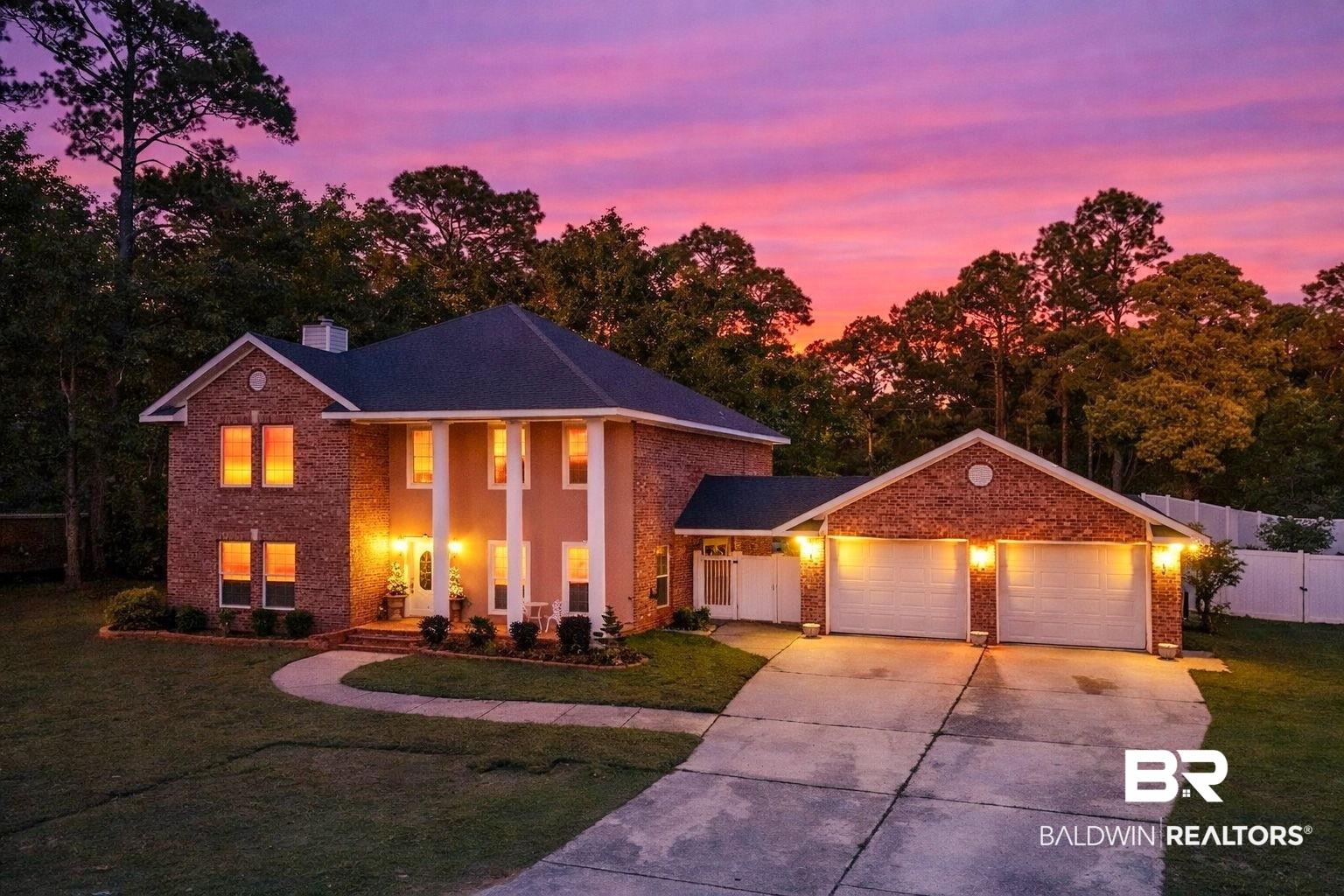 Image 2: View of front facade with driveway, an attached garage, covered porch, brick siding, and a chimney