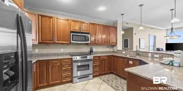 Image 3: Kitchen featuring wood cabinetry, stainless steel appliances, granite countertops, and tile flooring