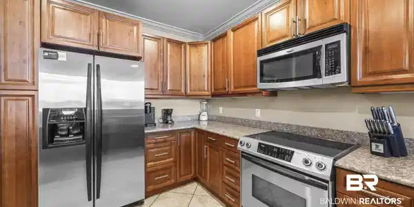 Image 4: Kitchen featuring abundant wood cabinetry, stone-look countertops, and tile flooring