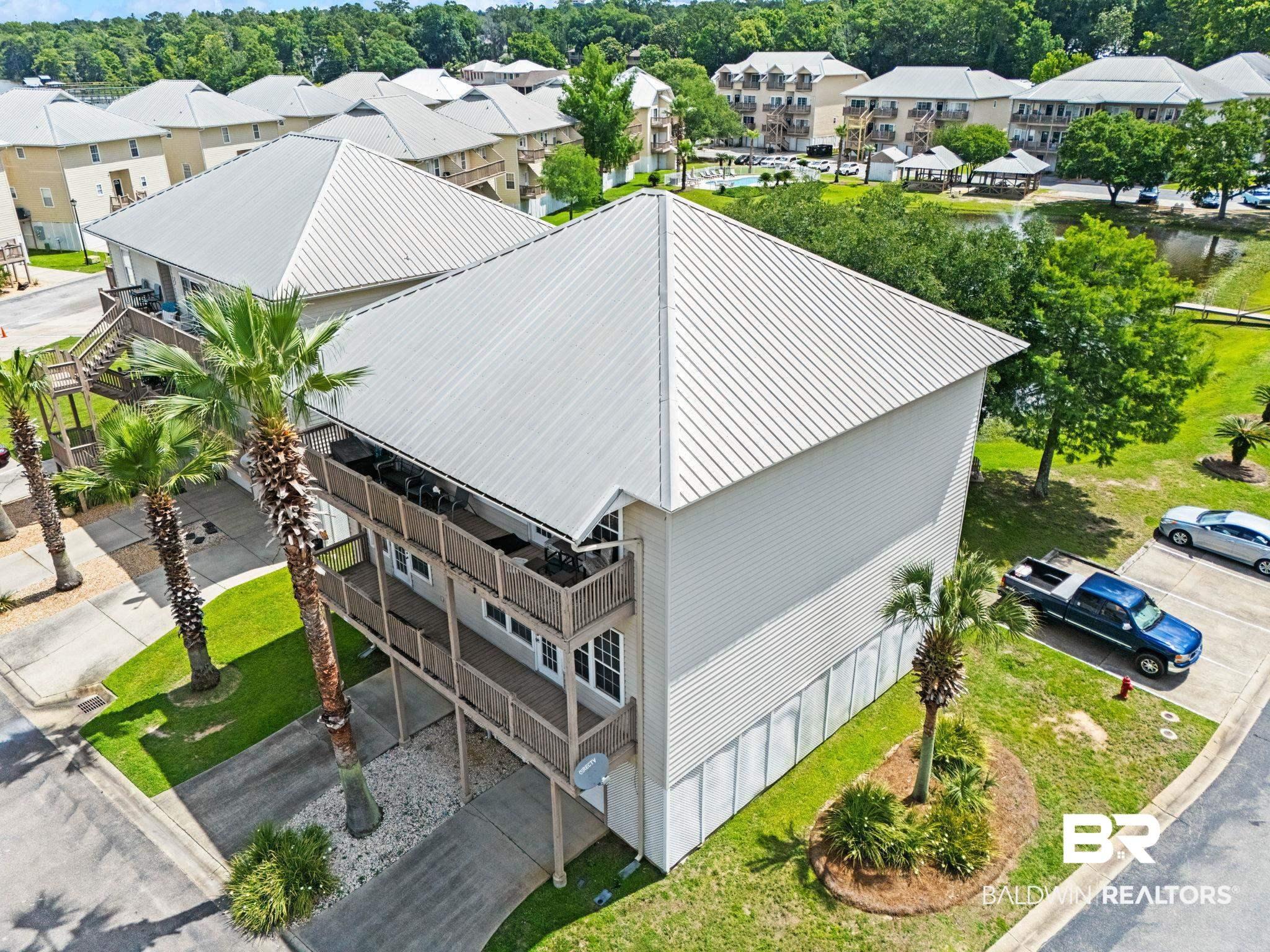 Image 3: Multi-level property featuring a metal roof, light-colored siding, and multiple balconies with dark railings