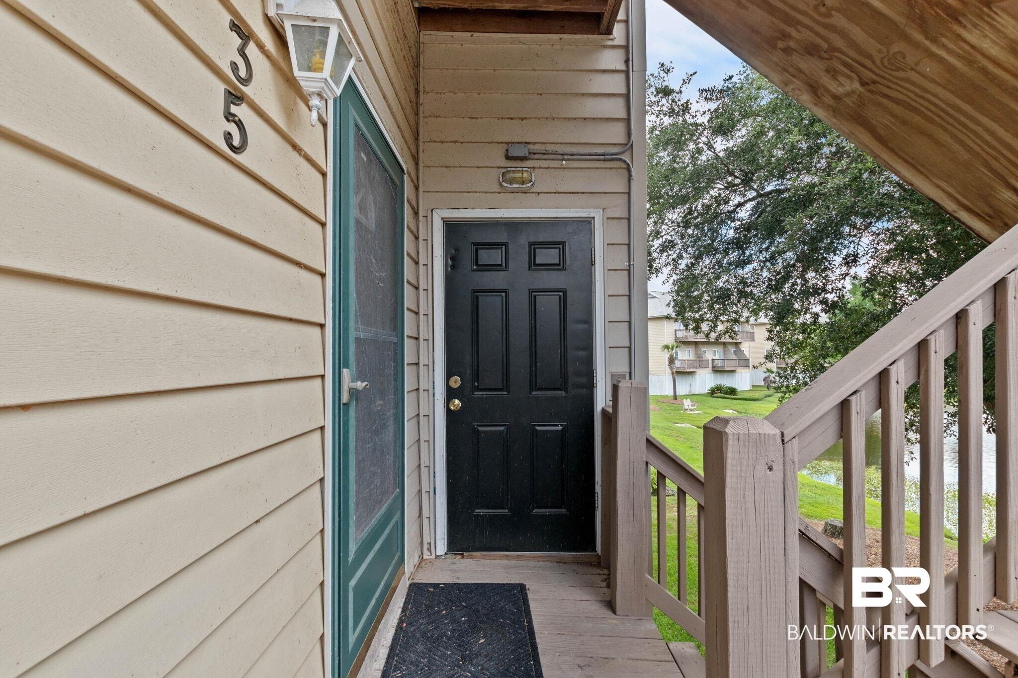 Image 4: Front entry featuring a paneled black door, screen door, and exterior sconce lighting