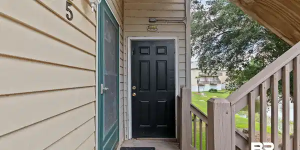 Image 4: Front entry featuring a paneled black door, screen door, and exterior sconce lighting