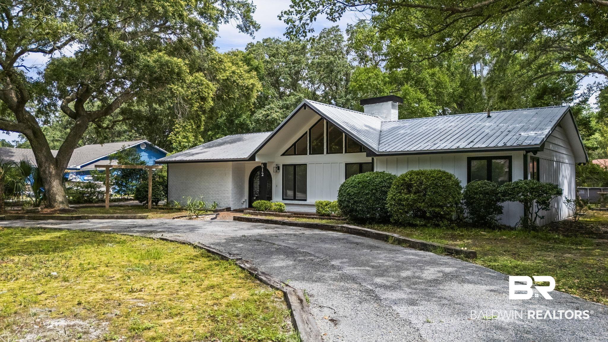 Image 4: Contemporary facade featuring white siding, a metal roof, and dark-framed windows