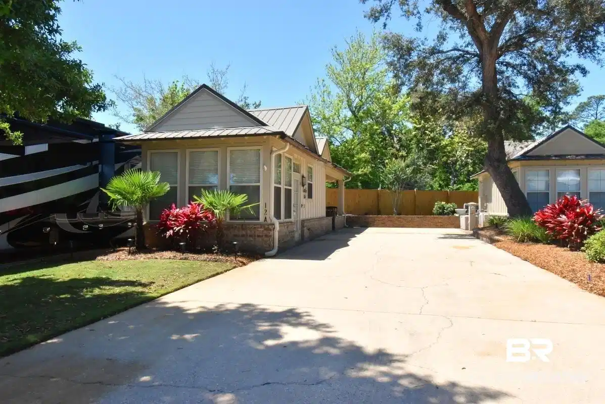 Image 1: View of property exterior featuring a metal roof, a sunroom, concrete driveway, a standing seam roof, and brick siding