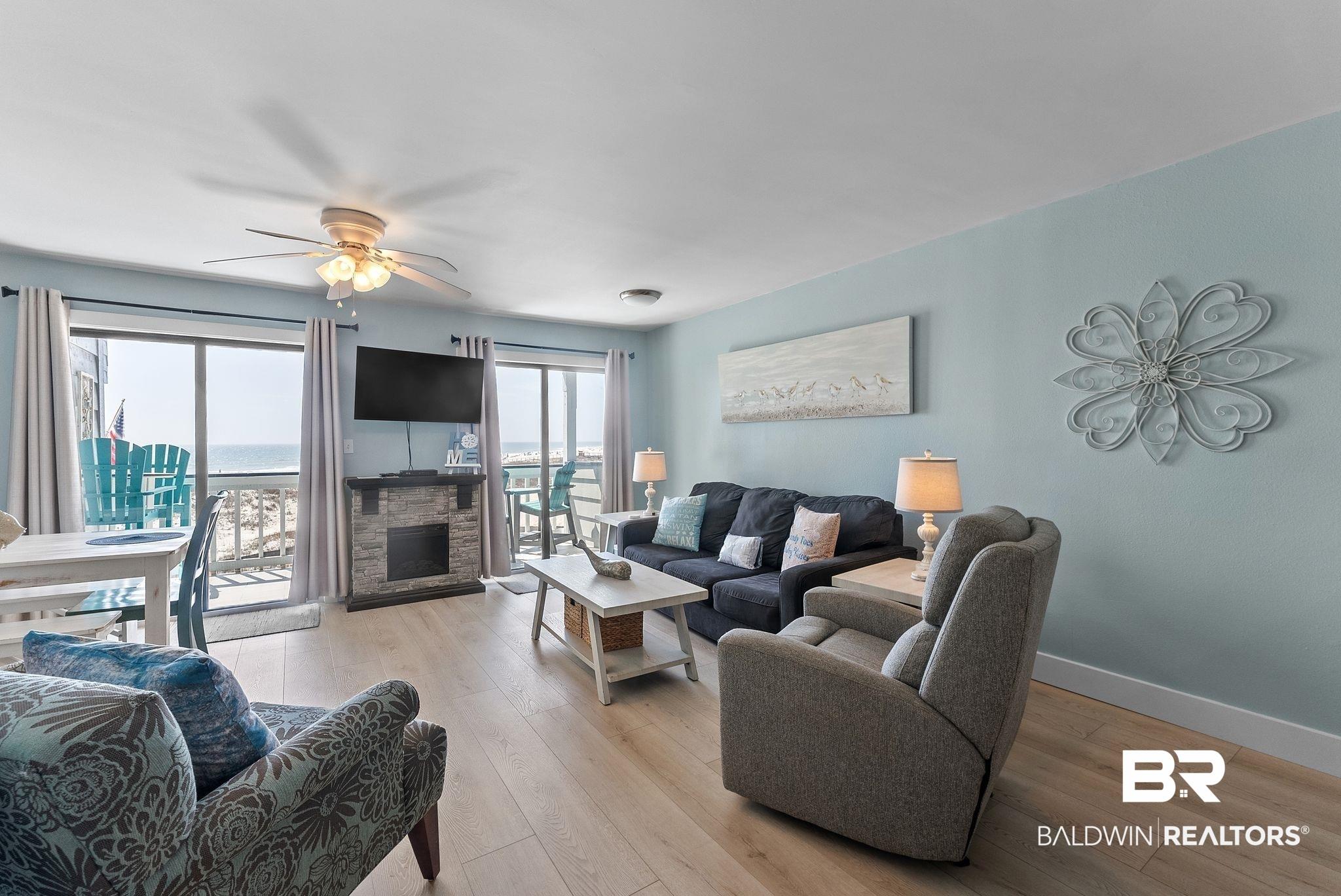Image 3: Living room featuring ceiling fan, light wood-type flooring, and a stone fireplace
