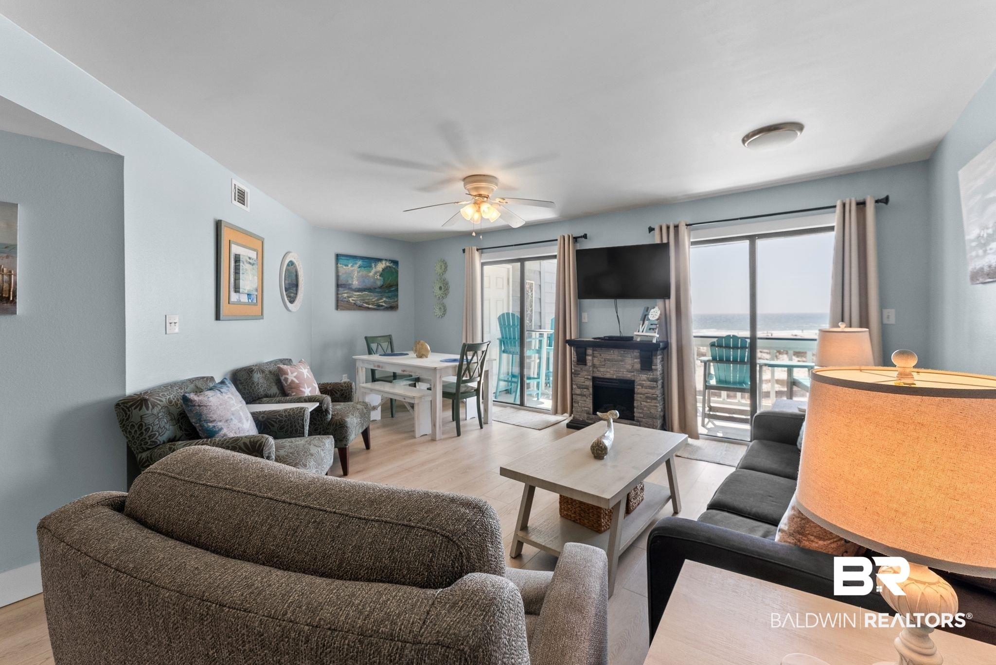 Image 4: Living area featuring ceiling fan, light wood-type flooring, and a stone fireplace