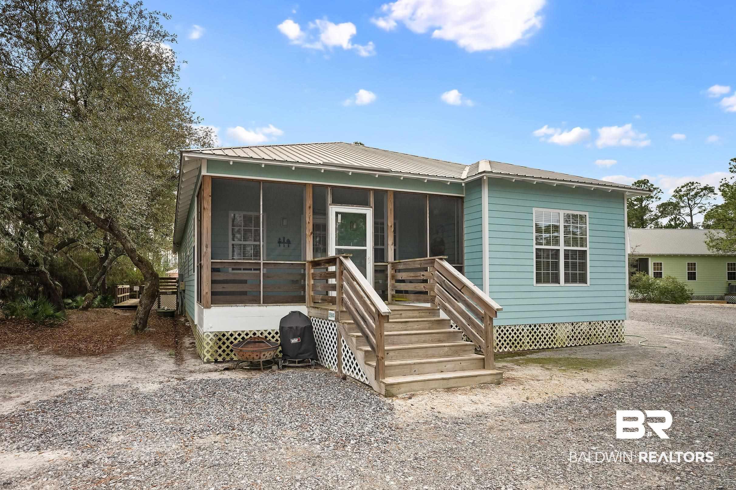 Image 2: View of front of house with a metal roof and a sunroom