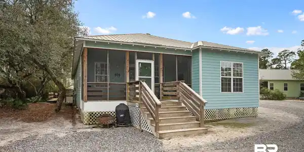 Image 2: View of front of house with a metal roof and a sunroom