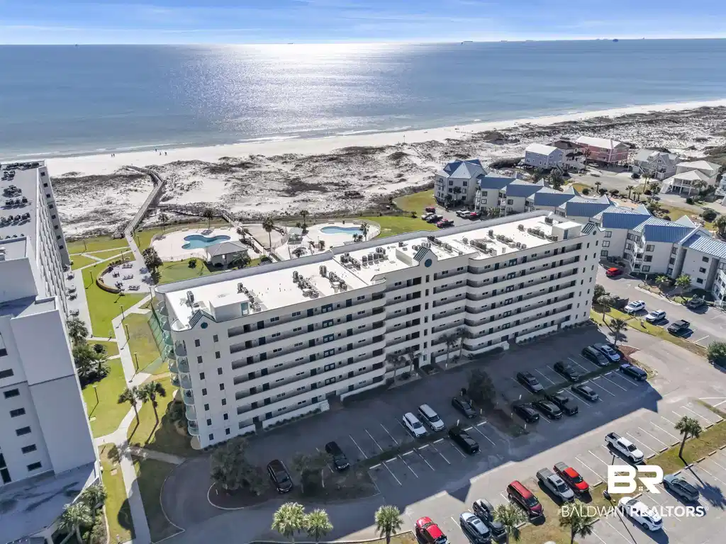 Image 1: Beachfront multi-story building featuring multiple balconies, on-site parking, two swimming pools, and direct beach access via a boardwalk