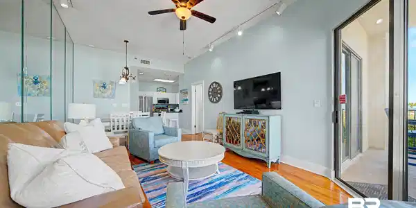 Image 2: Living area featuring wood-finish flooring, a ceiling fan with integrated lighting, and track lighting