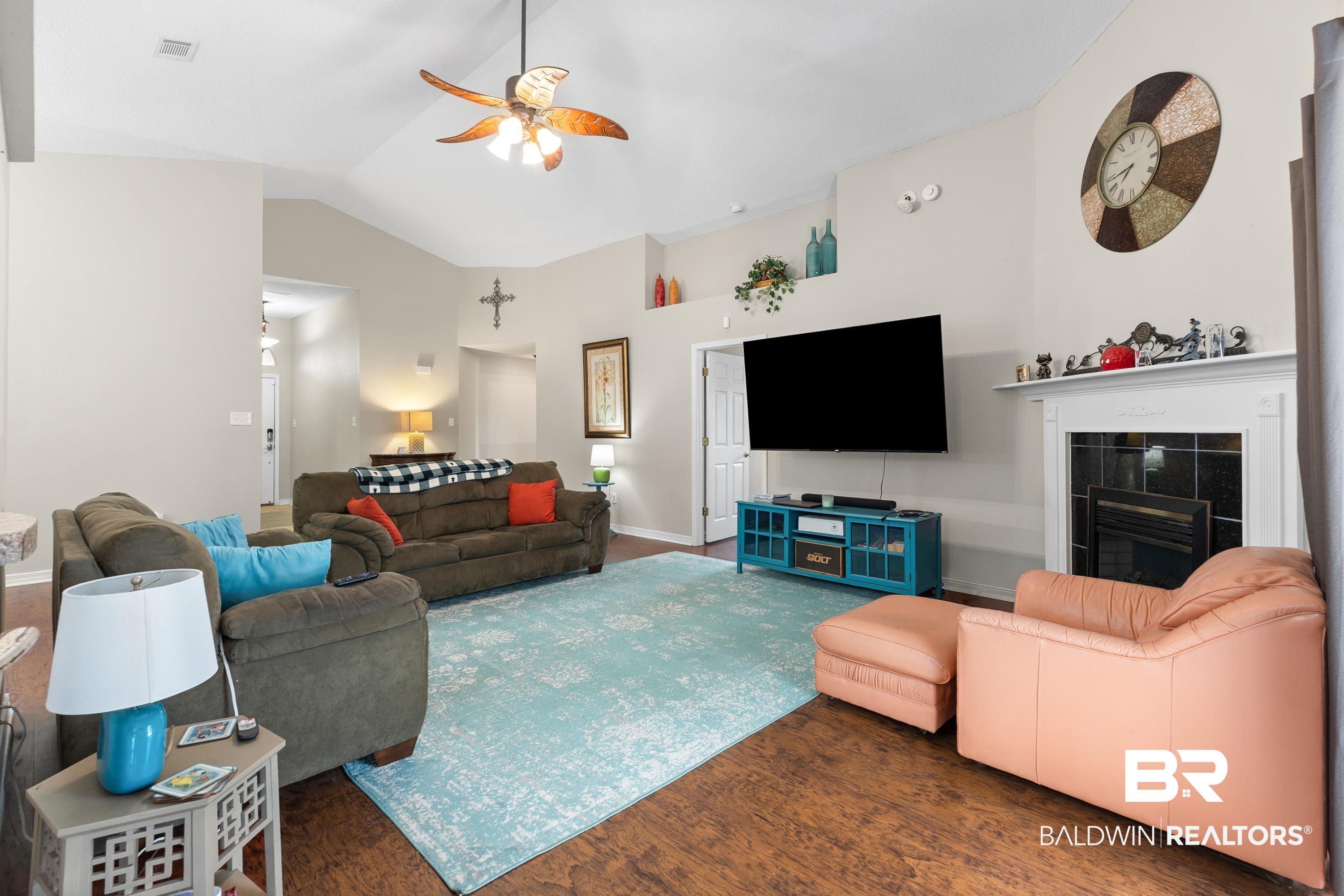 Image 2: Living room with ceiling fan, a tile fireplace, wood finished floors, and high vaulted ceiling