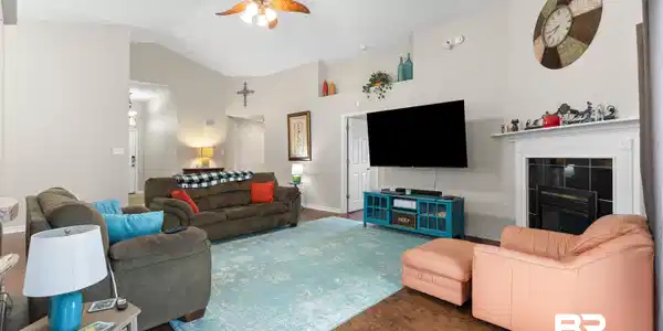 Image 2: Living room with ceiling fan, a tile fireplace, wood finished floors, and high vaulted ceiling