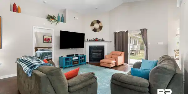 Image 4: Living area with a tiled fireplace, a ceiling fan, wood finished floors, and high vaulted ceiling