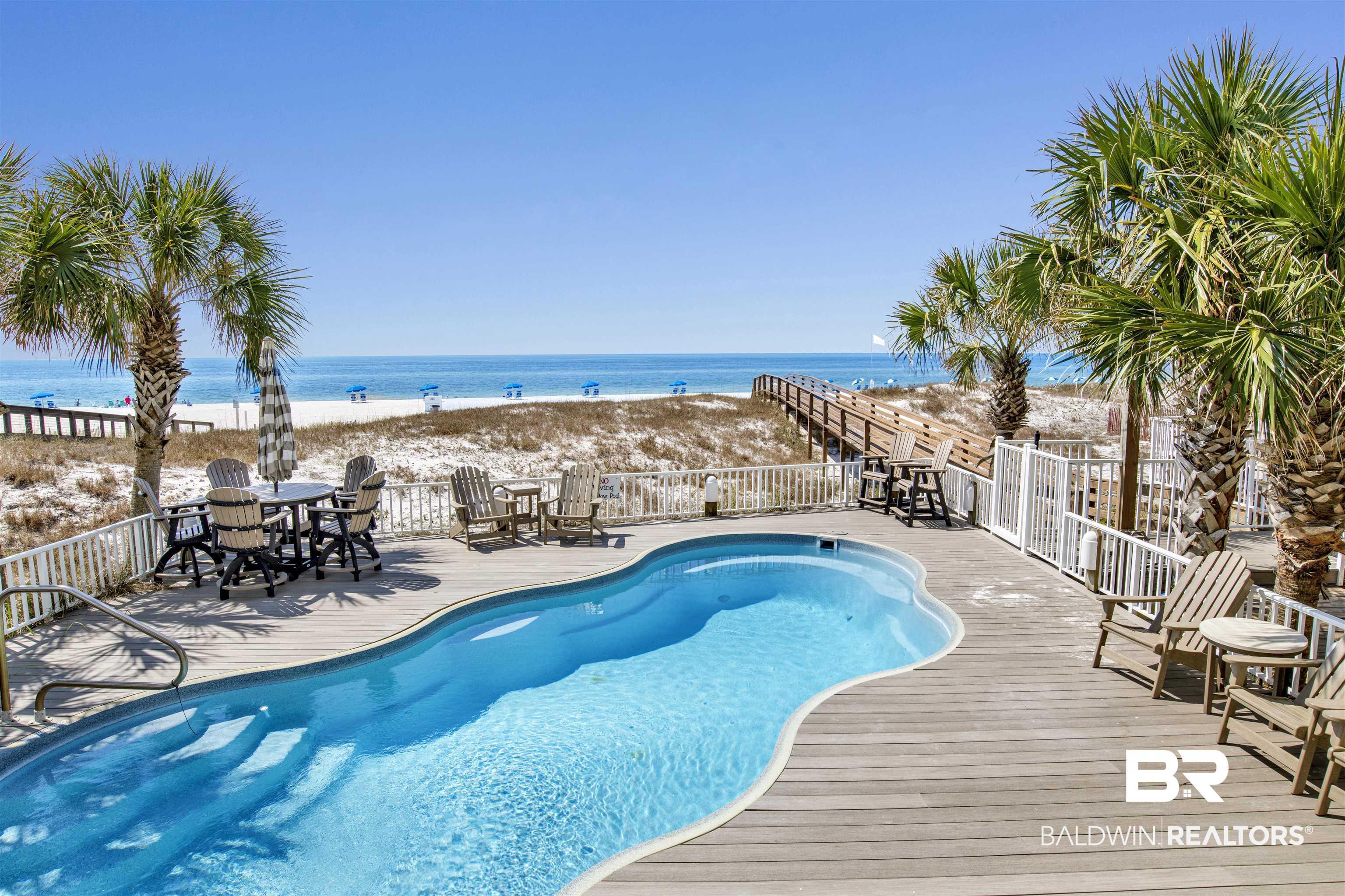 Image 3: View of swimming pool featuring a beach view, a fenced in pool, a deck with water view, and fence