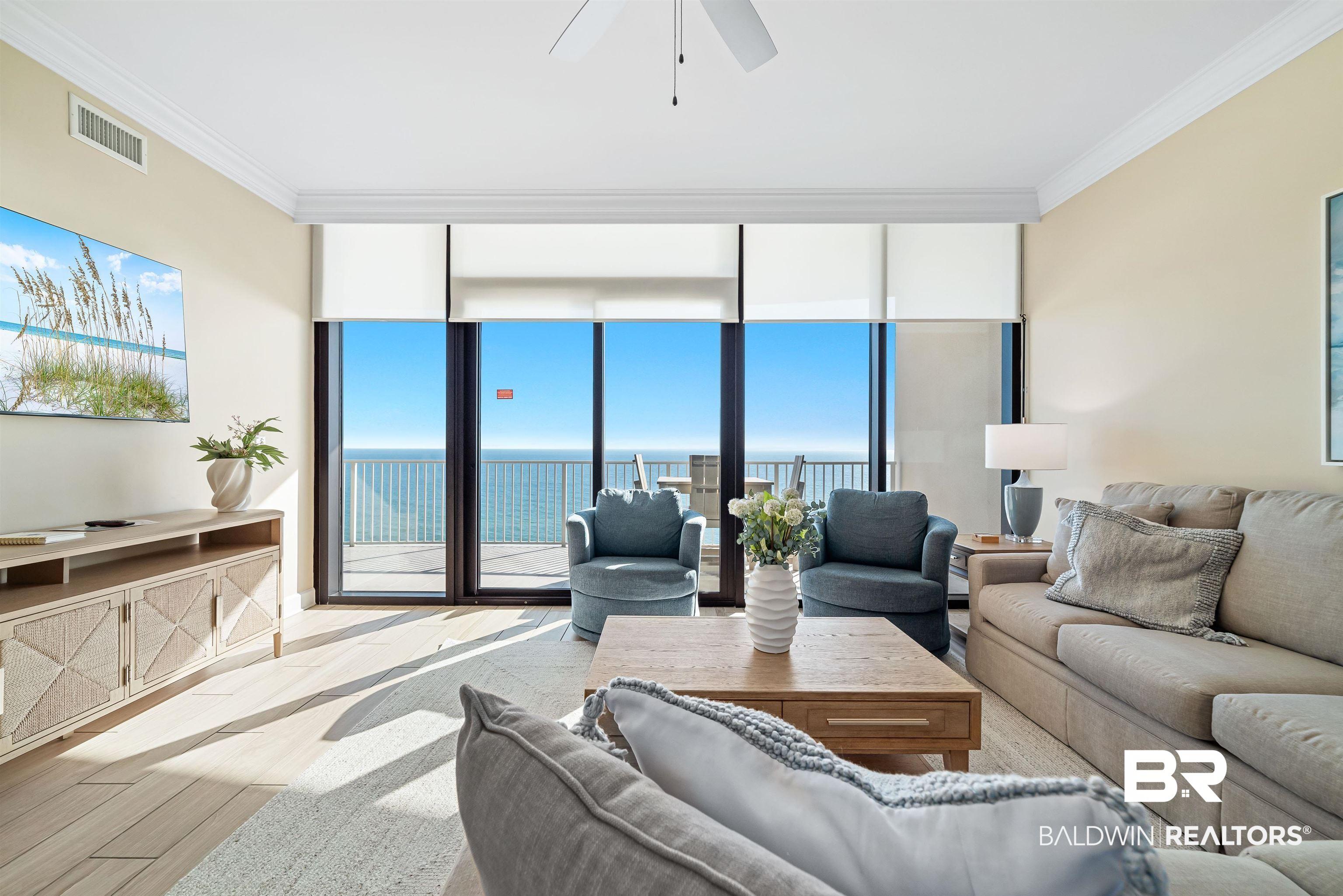 Image 3: Living area featuring wood finished floors, expansive windows, ornamental molding, a water view, and a ceiling fan