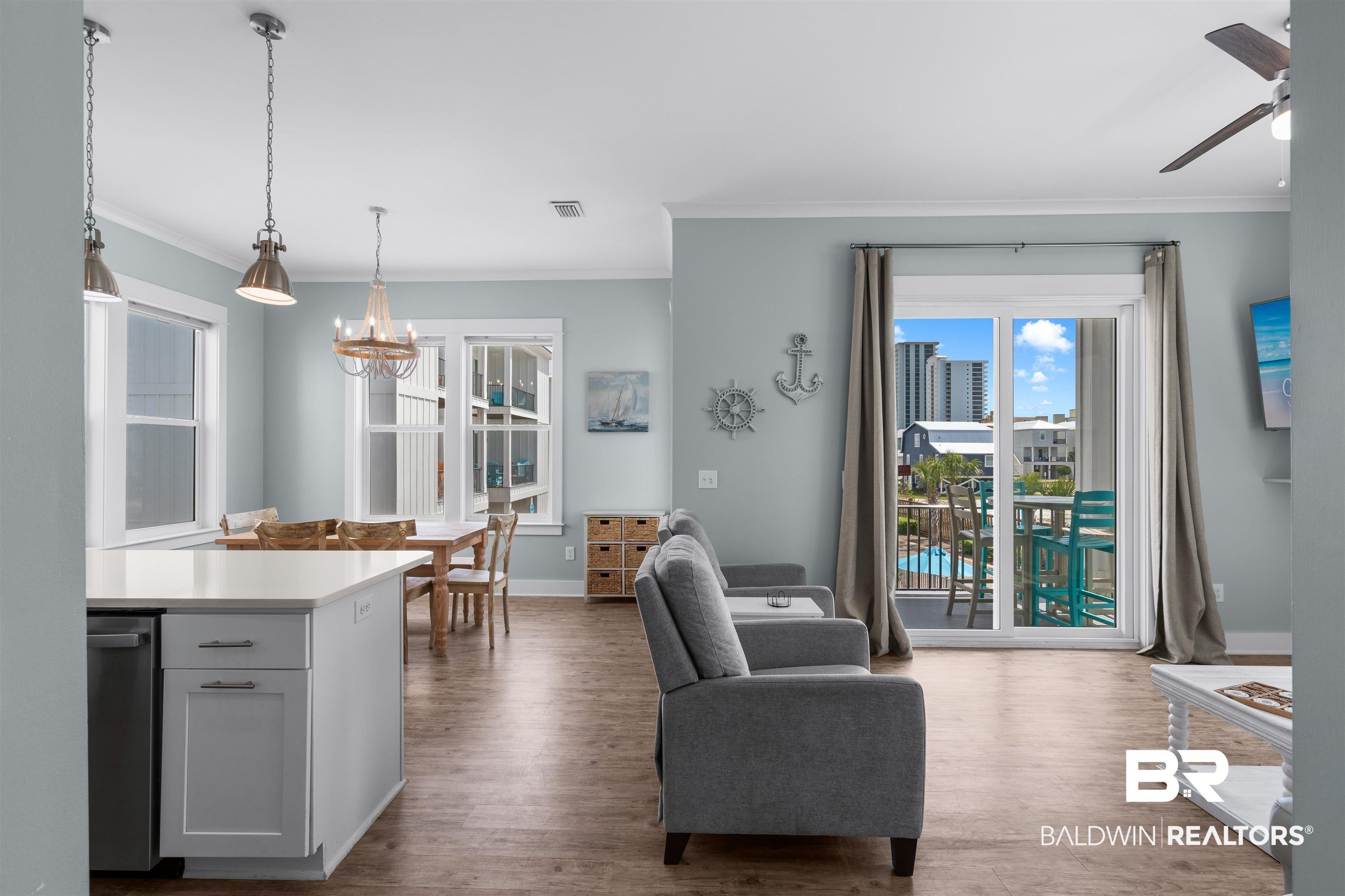 Image 2: Open-concept living area with wood-finish flooring, a kitchen island with a light countertop, and a dining space