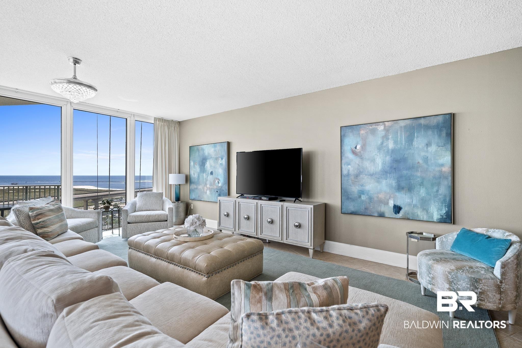 Image 2: Living area with floor to ceiling windows, baseboards, and a textured ceiling