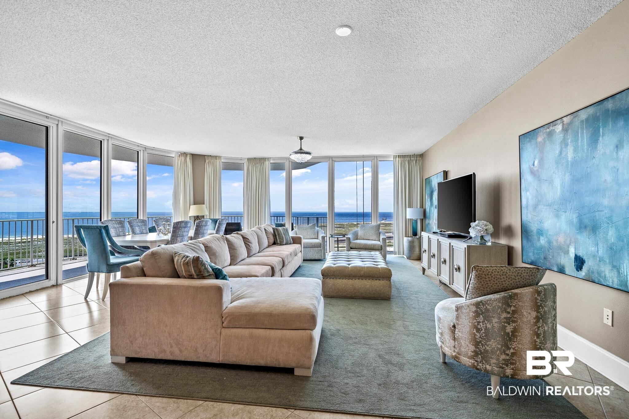 Image 3: Living room featuring tile patterned flooring, expansive windows, baseboards, and a textured ceiling