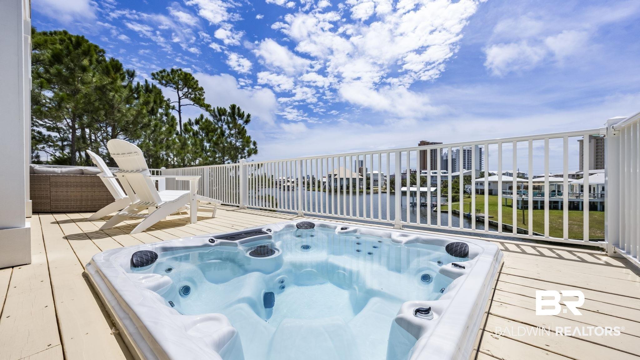 Image 3: Outdoor hot tub situated on a wood-finish deck with white railing