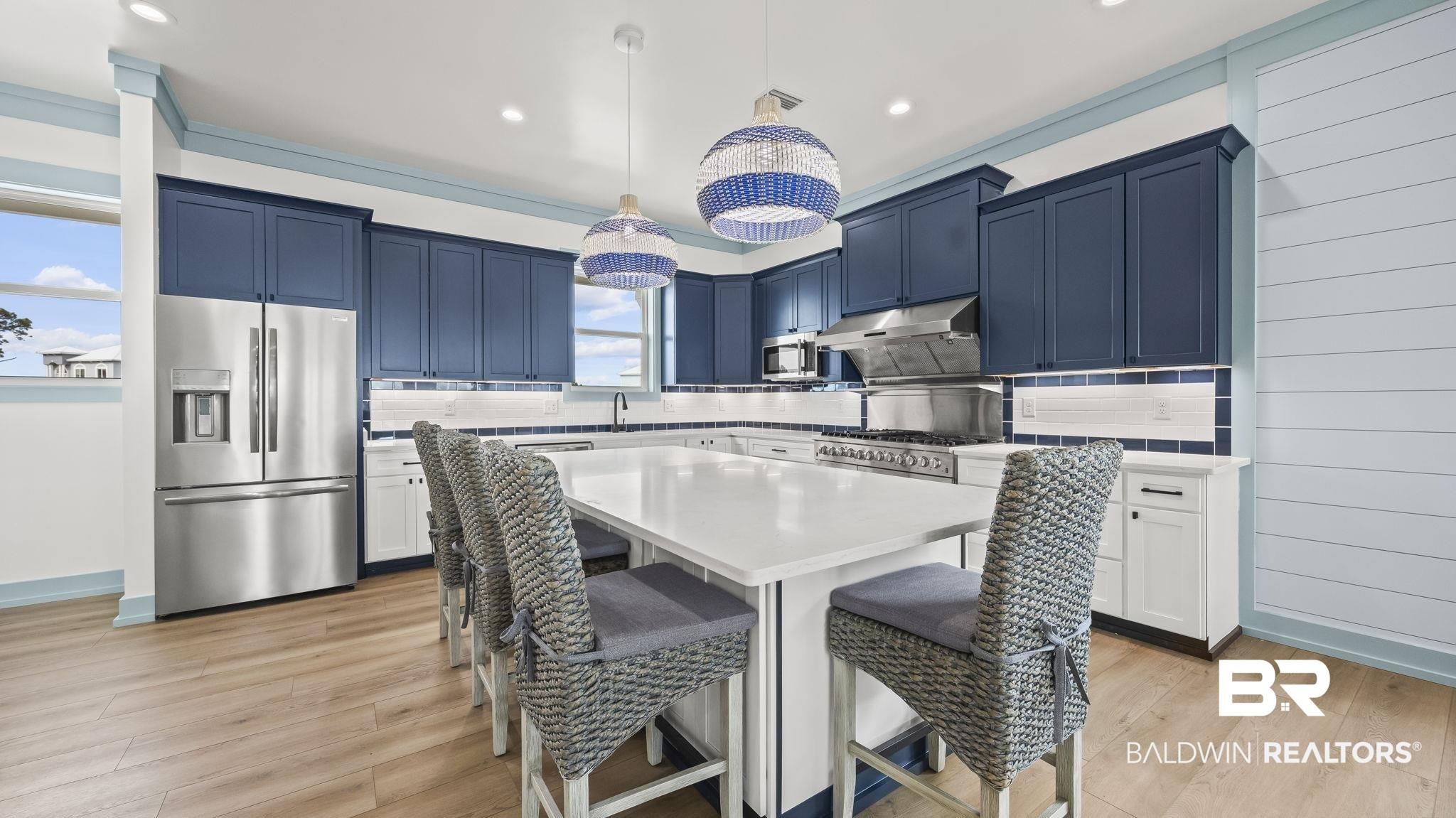 Image 4: Kitchen with stainless steel refrigerator with ice dispenser, a breakfast bar, pendant lighting, a center island, and backsplash