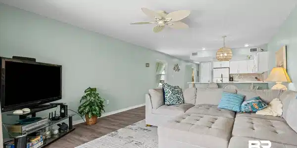 Image 3: Spacious living area featuring light green walls and wood-finish flooring