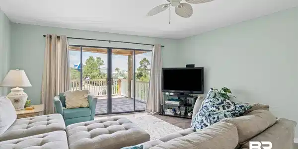 Image 4: Spacious living area featuring light green walls, a ceiling fan, and dark wood-finish flooring