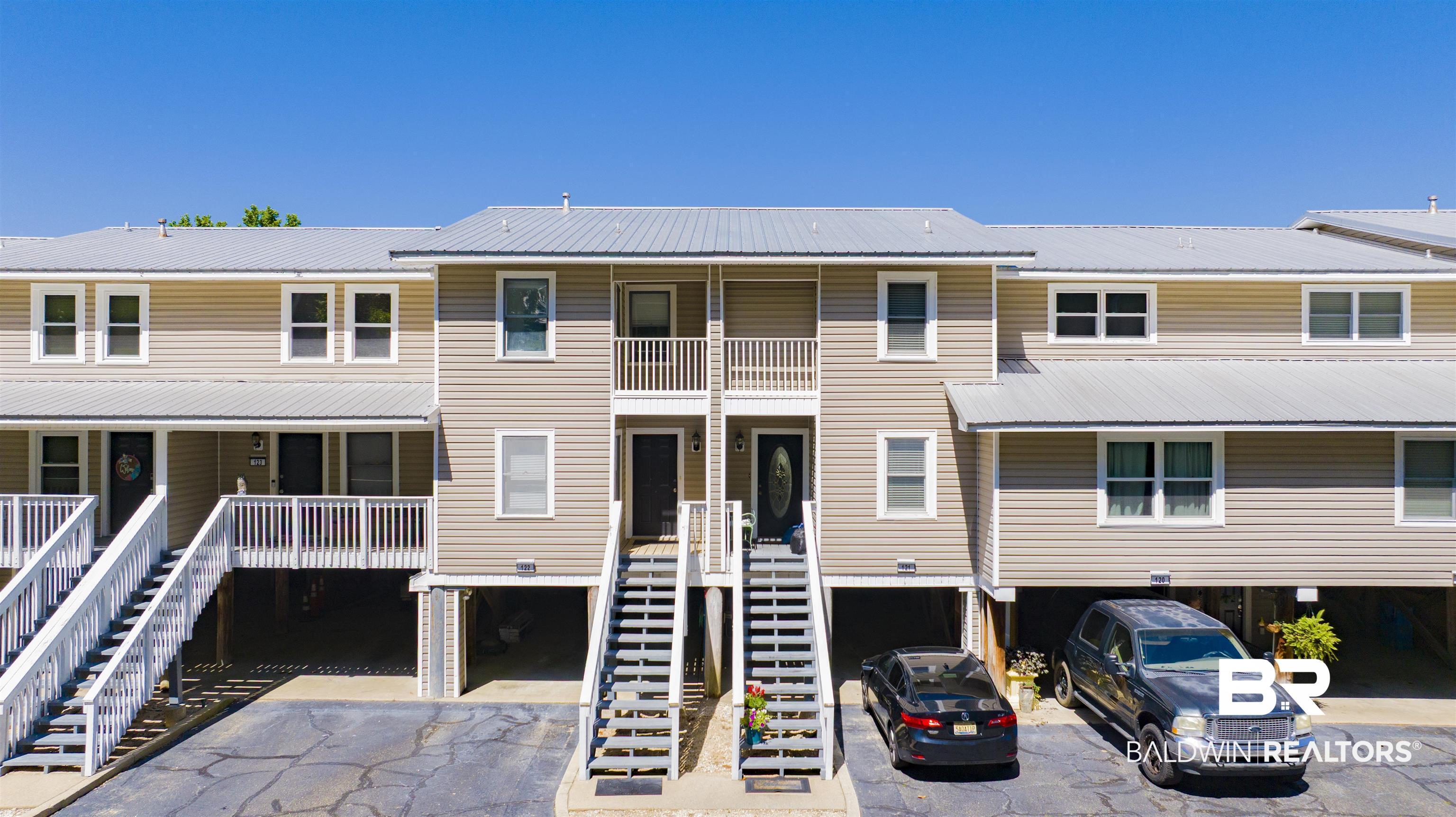 Image 1: Multi-story residential building featuring light brown siding and a metal roof