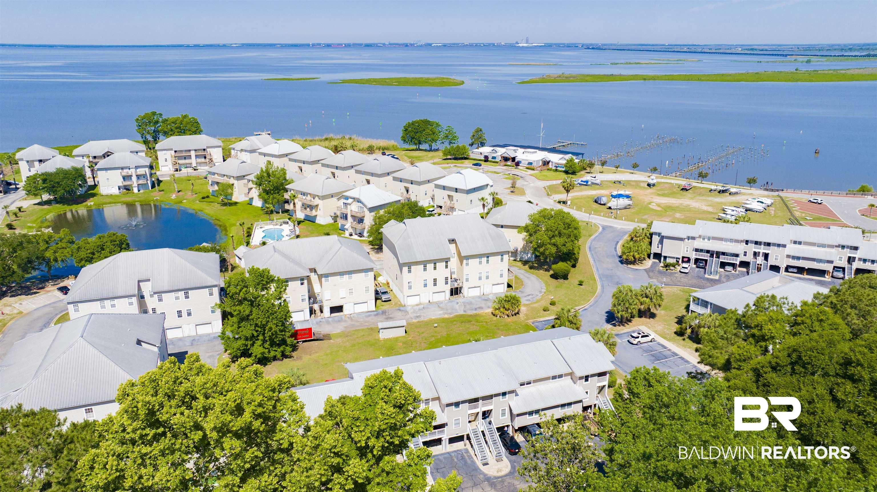 Image 2: Expansive waterfront community featuring multiple residential buildings, a central pond, and a community swimming pool