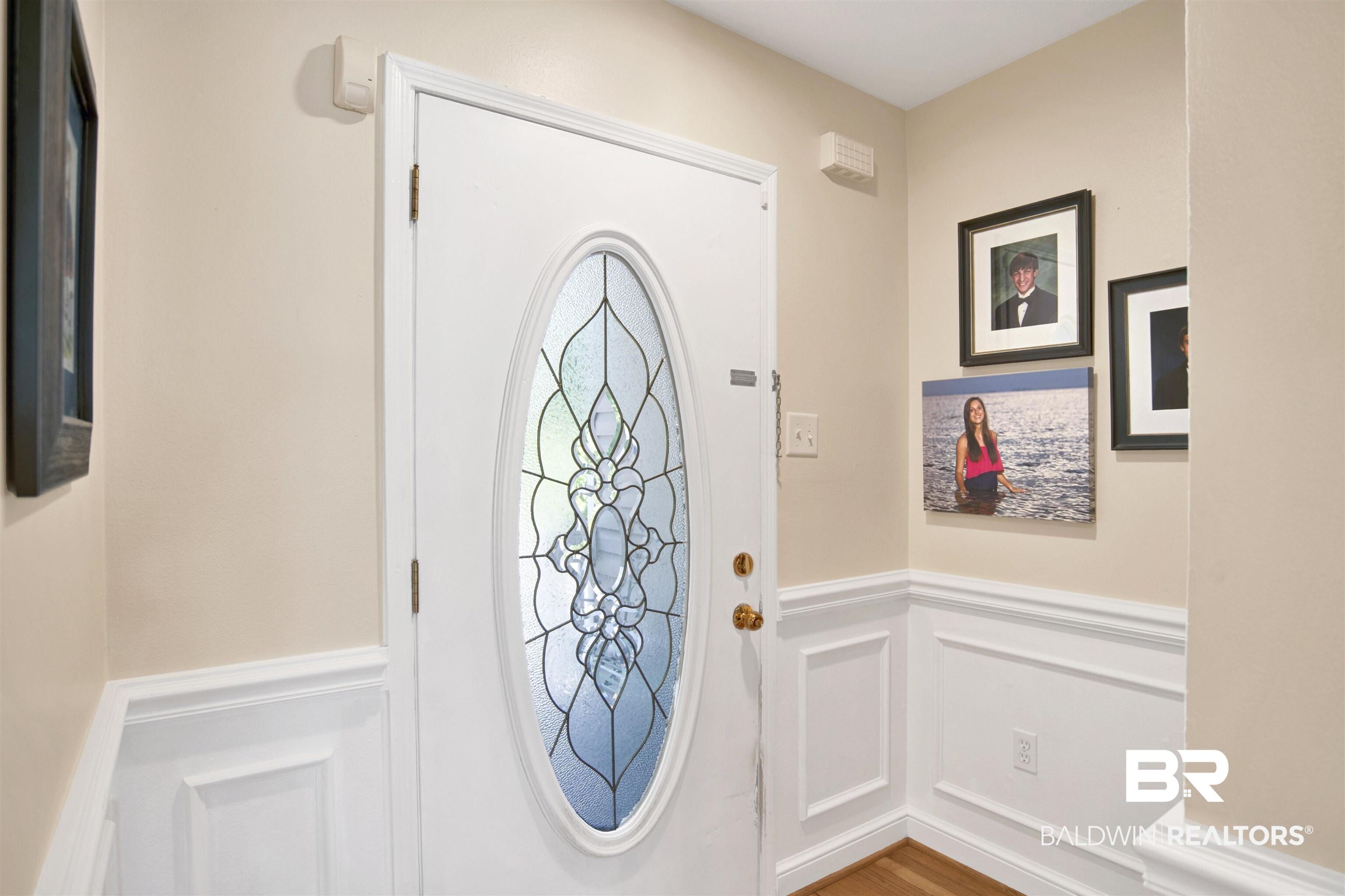 Image 4: Entry door with an oval leaded glass insert, brass hardware, and white trim