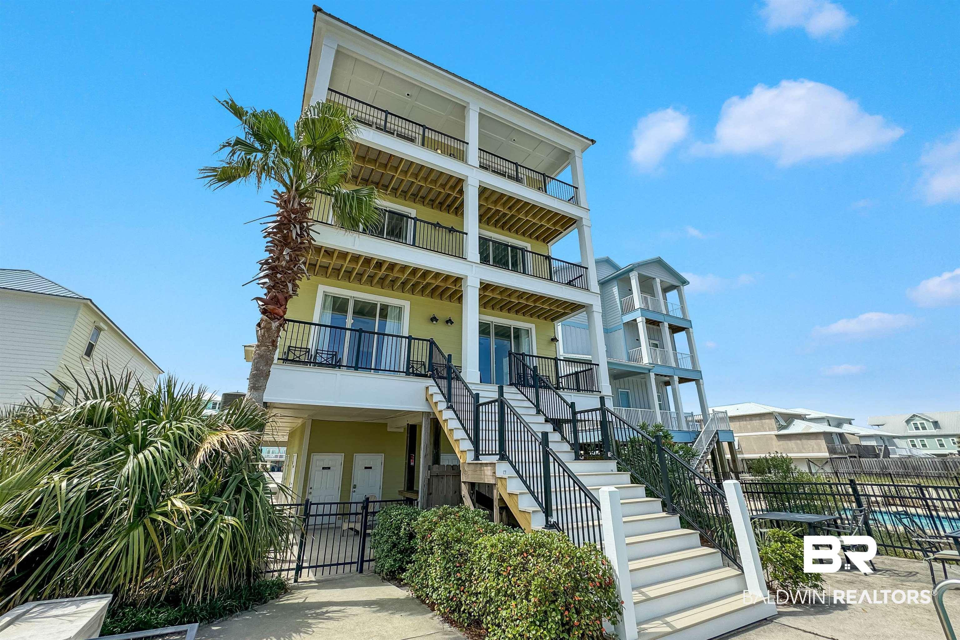 Image 2: Multi-story residence featuring a pale yellow exterior, multiple balconies with black railings, and a prominent palm tree