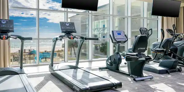 Image 4: Fitness area featuring floor-to-ceiling windows, multiple wall-mounted televisions, and carpeting
