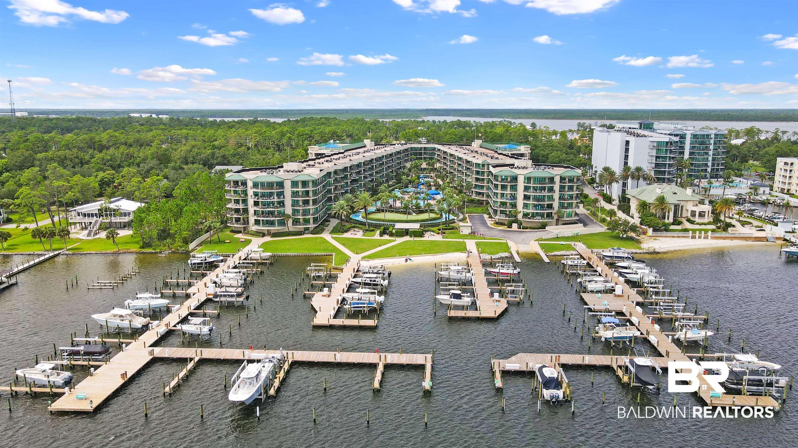 Image 1: Waterfront condominium complex featuring a private marina with multiple boat slips, direct water access, and a sandy shore