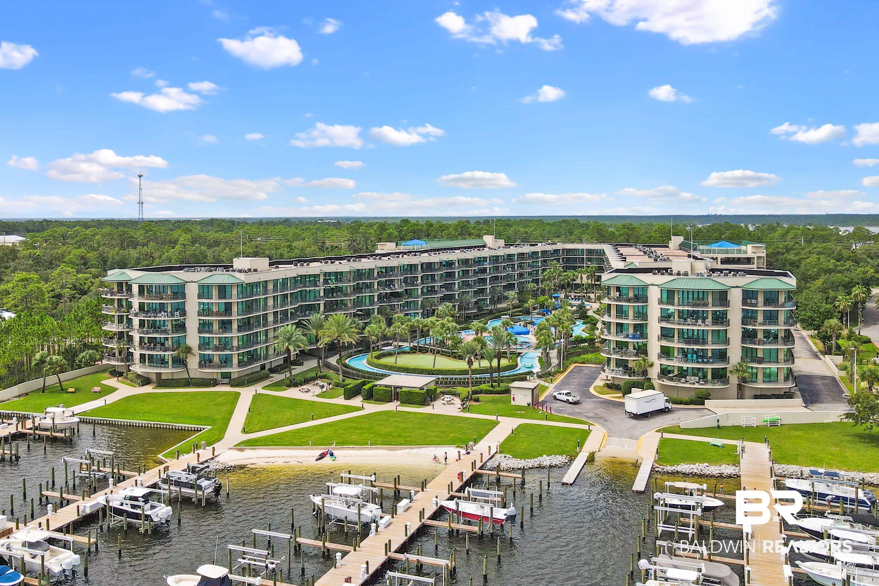 Image 2: Expansive waterfront condominium complex featuring multiple residential buildings, a marina with numerous boat slips, a central pool area with landscaping, a putting green, and direct water access