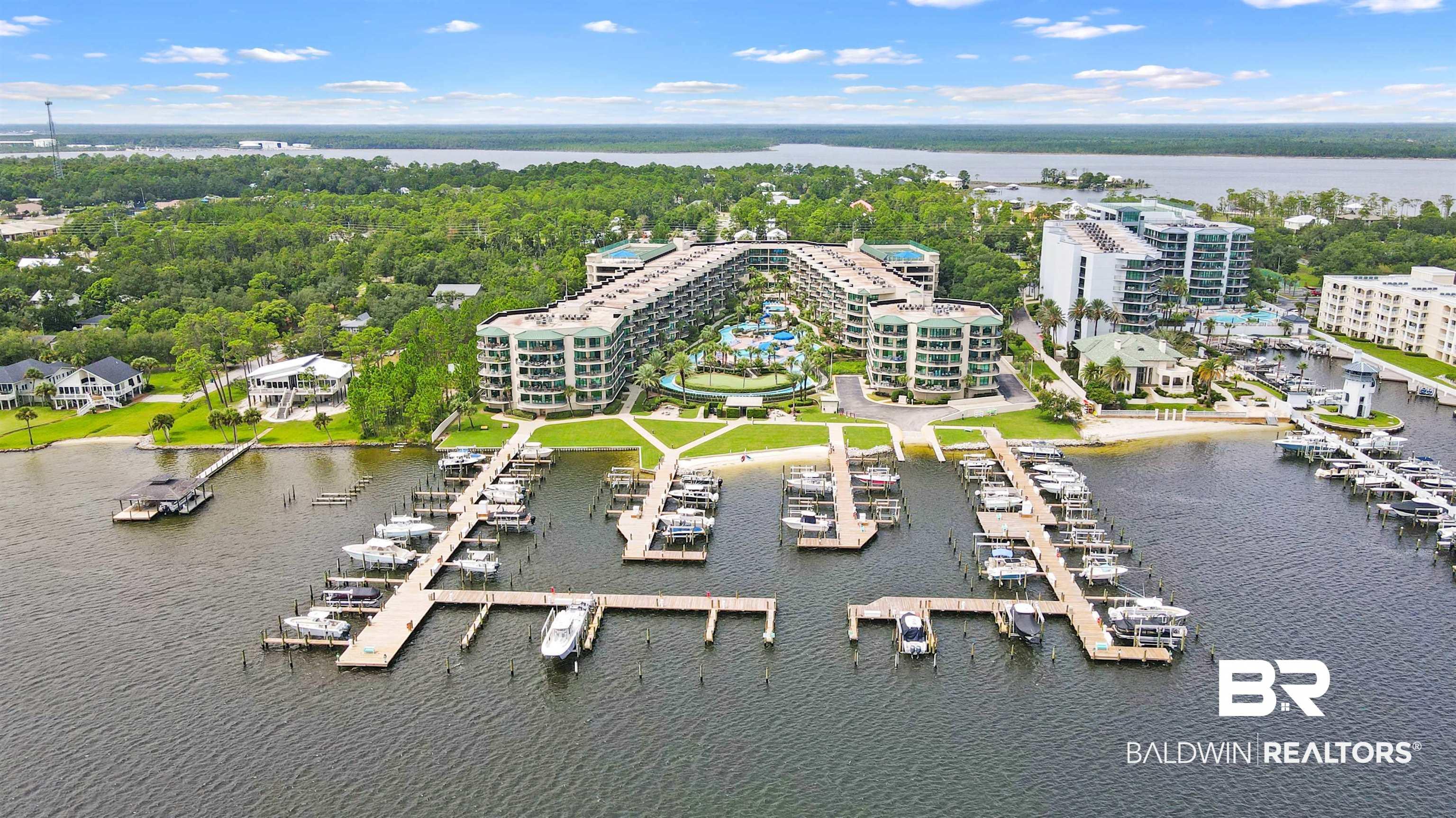 Image 4: Expansive waterfront property featuring multiple residential buildings, private docks with numerous boat slips, a sandy shoreline, and a substantial green space