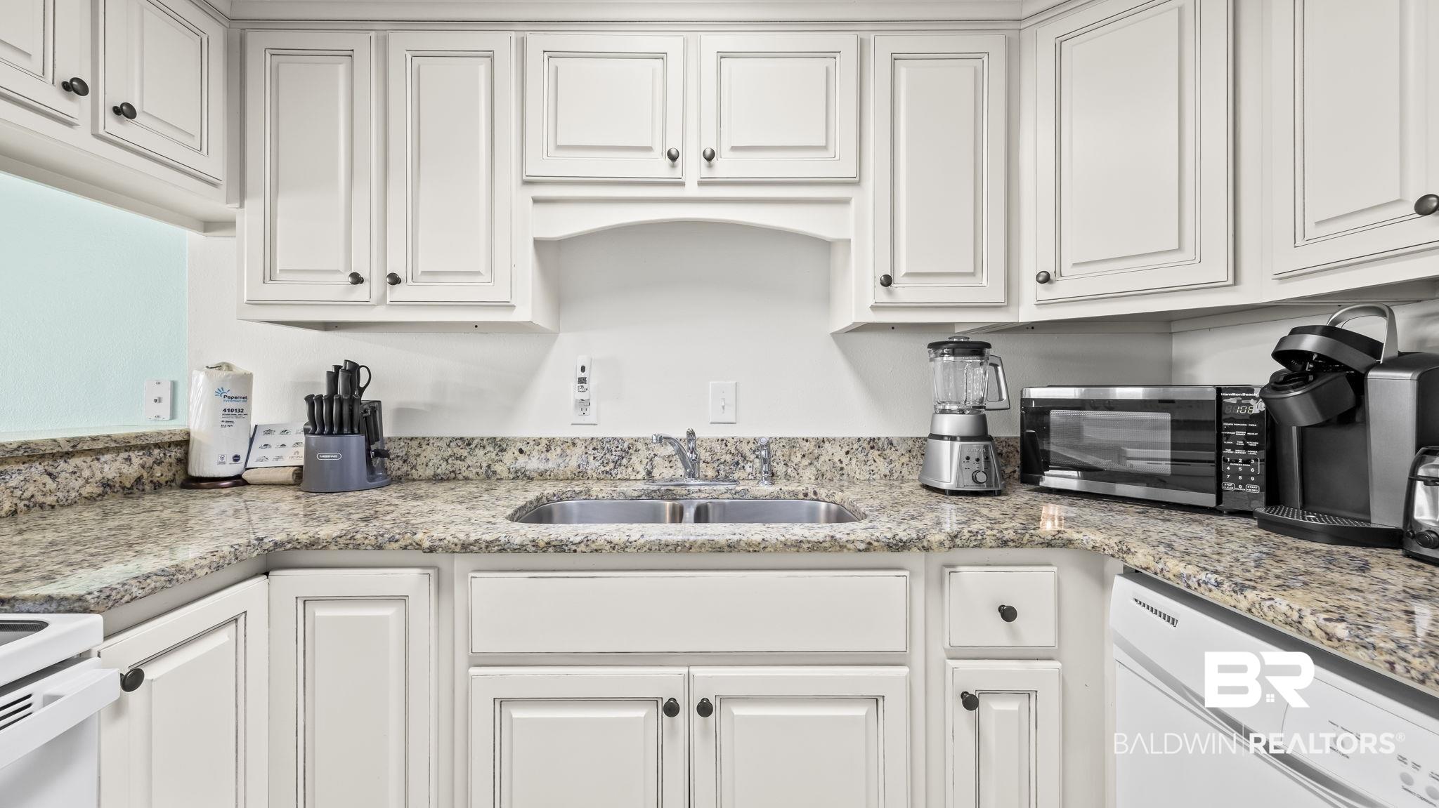 Image 3: Kitchen featuring white appliances, white cabinetry, and light stone countertops