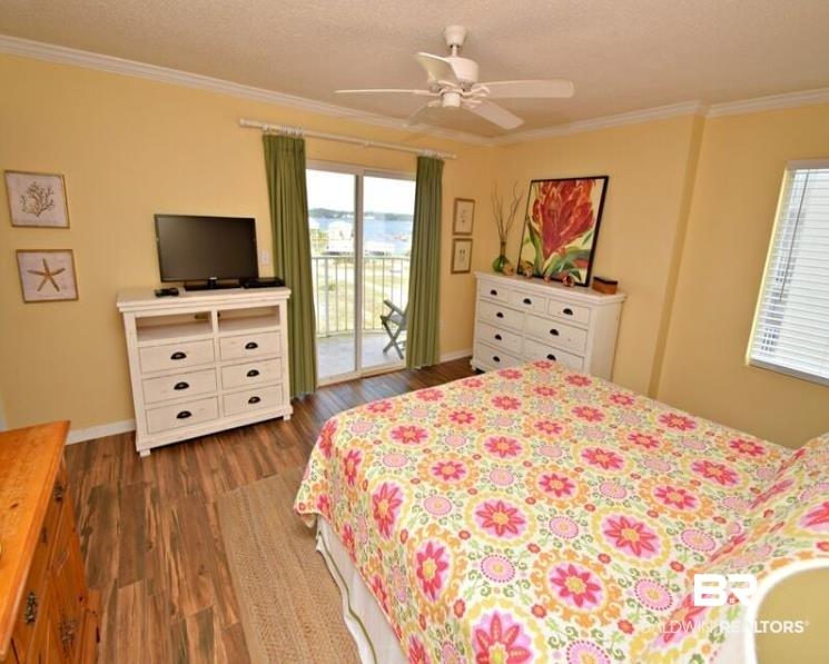 Image 2: Bedroom featuring dark wood-style floors, access to exterior, ornamental molding, ceiling fan, and a textured ceiling