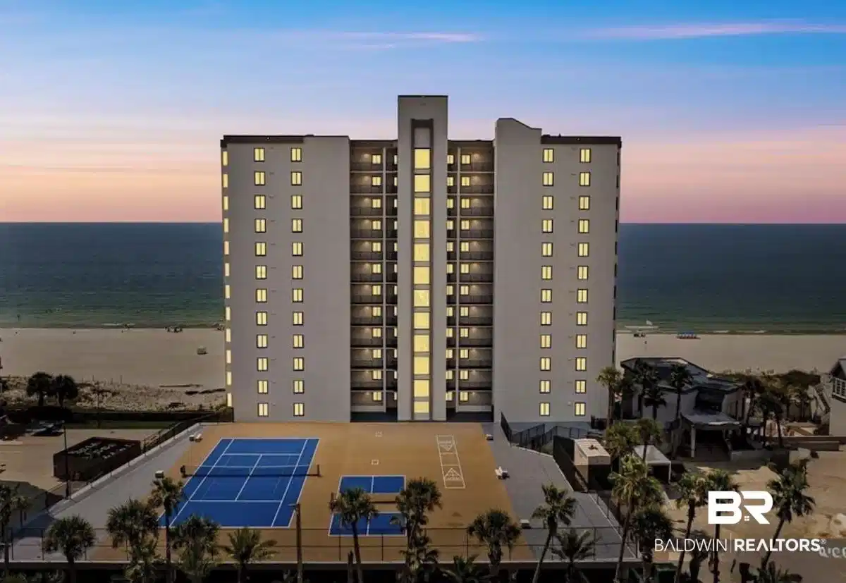 Image 1: Property at dusk with view of water and beach and a view of apartment building / complex