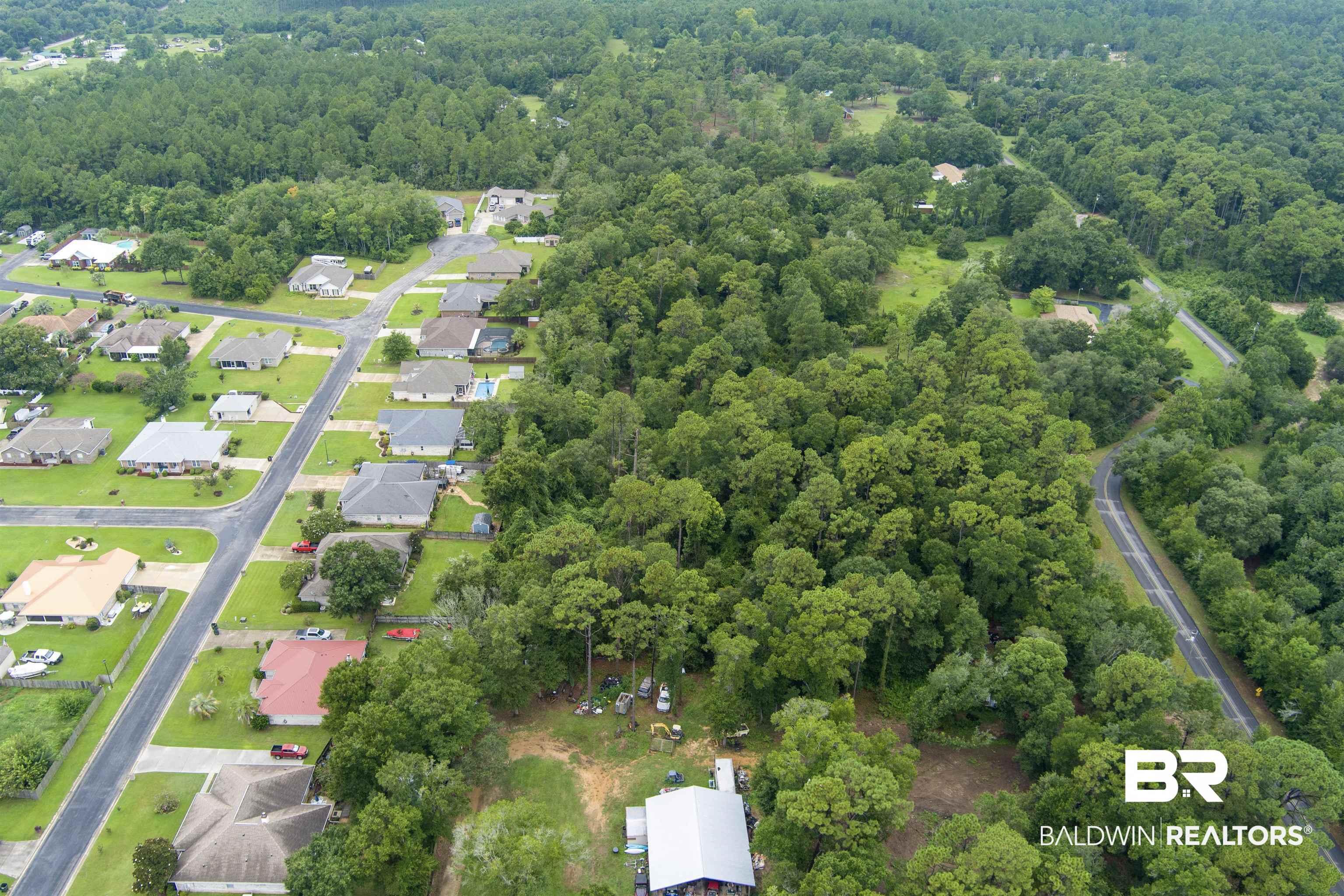 Image 4: Aerial view of residential area featuring a heavily wooded area