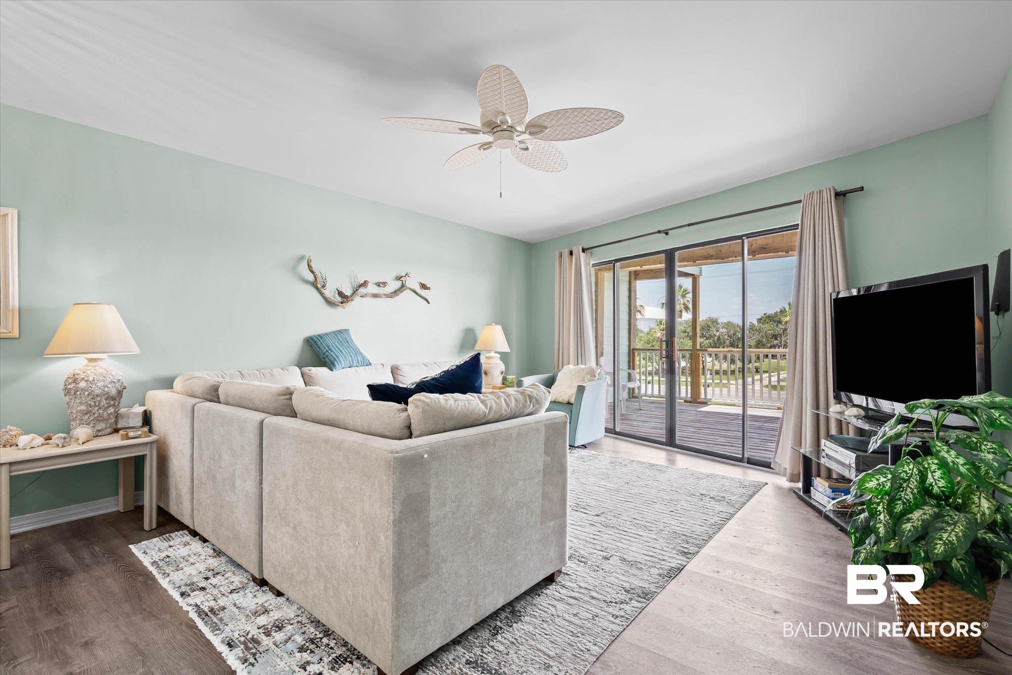Image 2: Living area featuring wood-finish flooring, a ceiling fan, and direct access to an outdoor deck through sliding glass doors