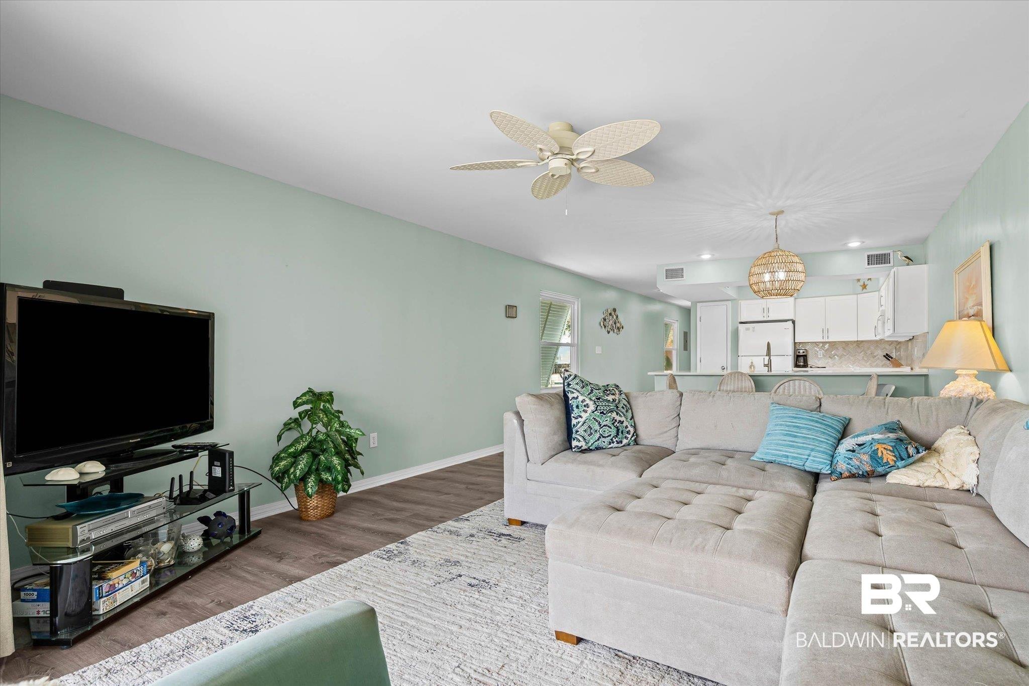 Image 3: Spacious living area featuring light green walls and wood-finish flooring