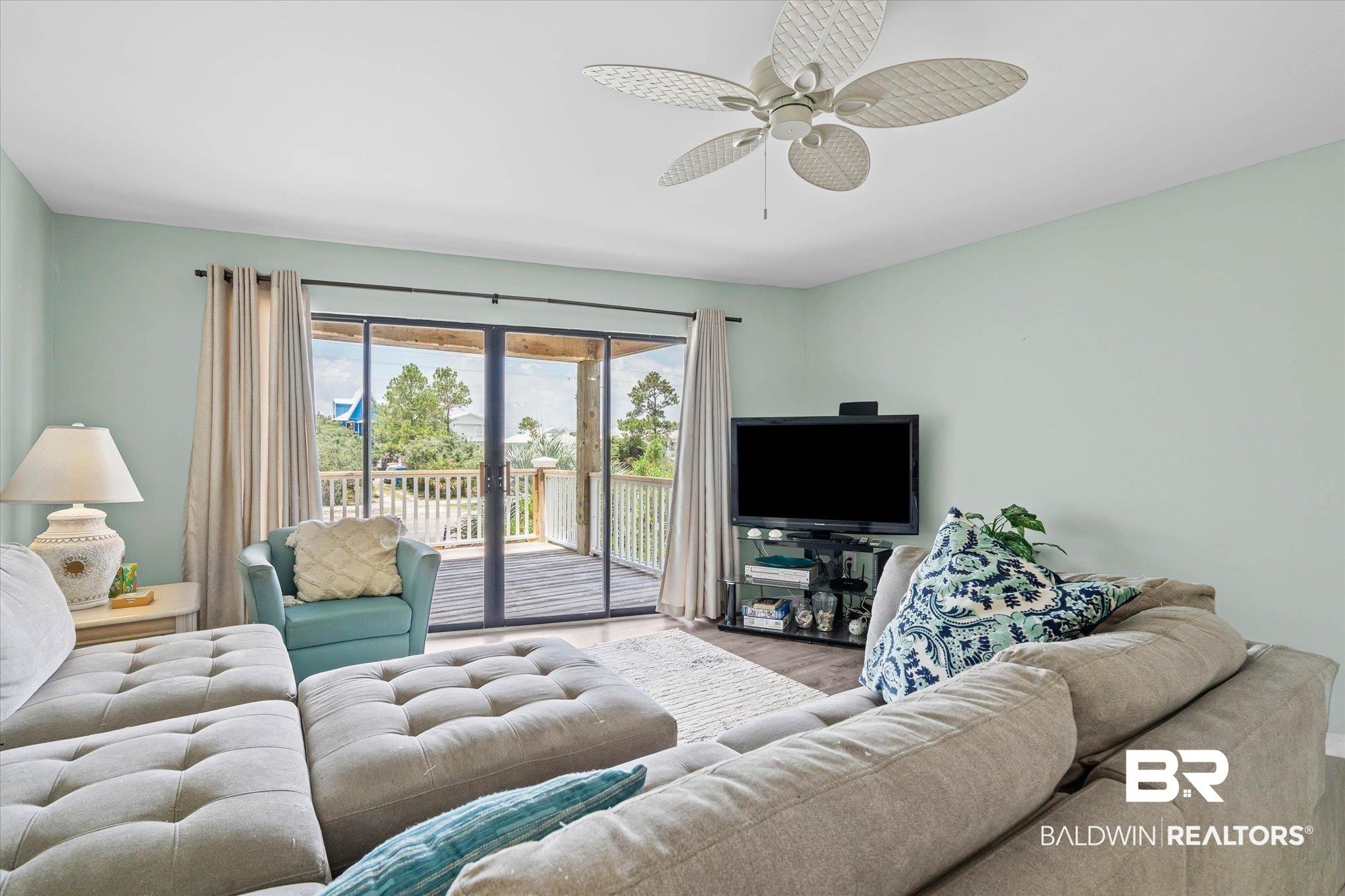 Image 4: Spacious living area featuring light green walls, a ceiling fan, and dark wood-finish flooring
