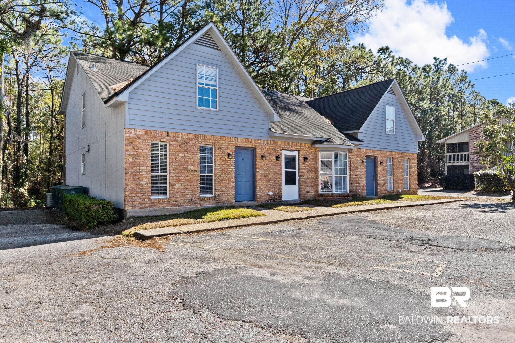 Image 3: View of front of property featuring brick siding, a shingled roof, and uncovered parking