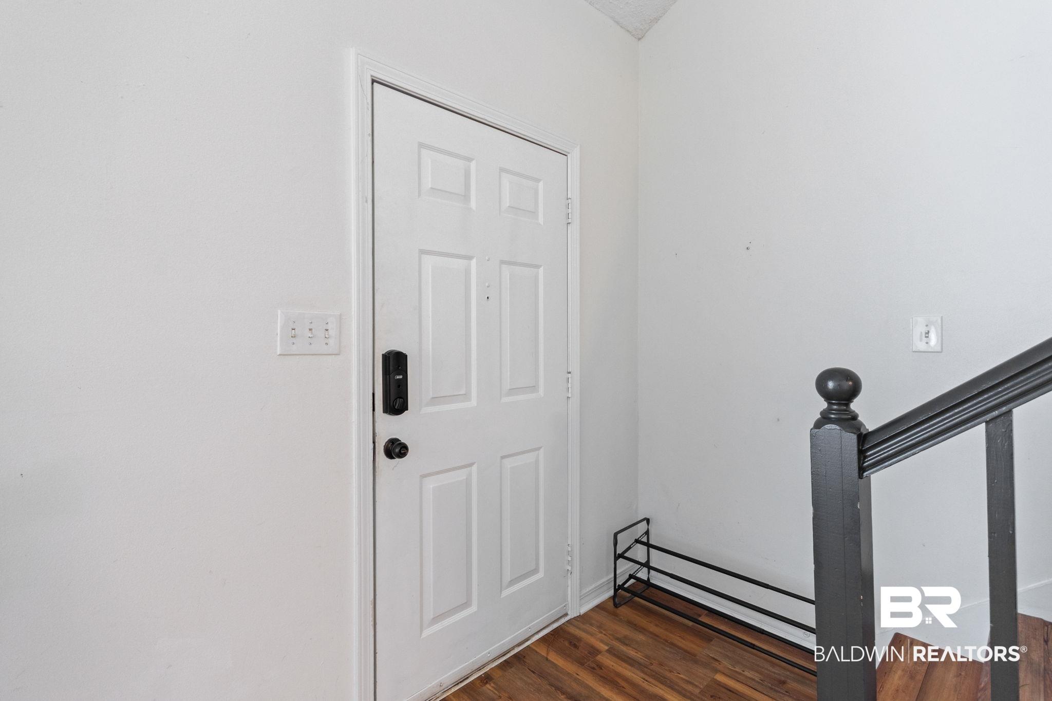 Image 4: Entrance foyer with dark wood-style floors and stairs